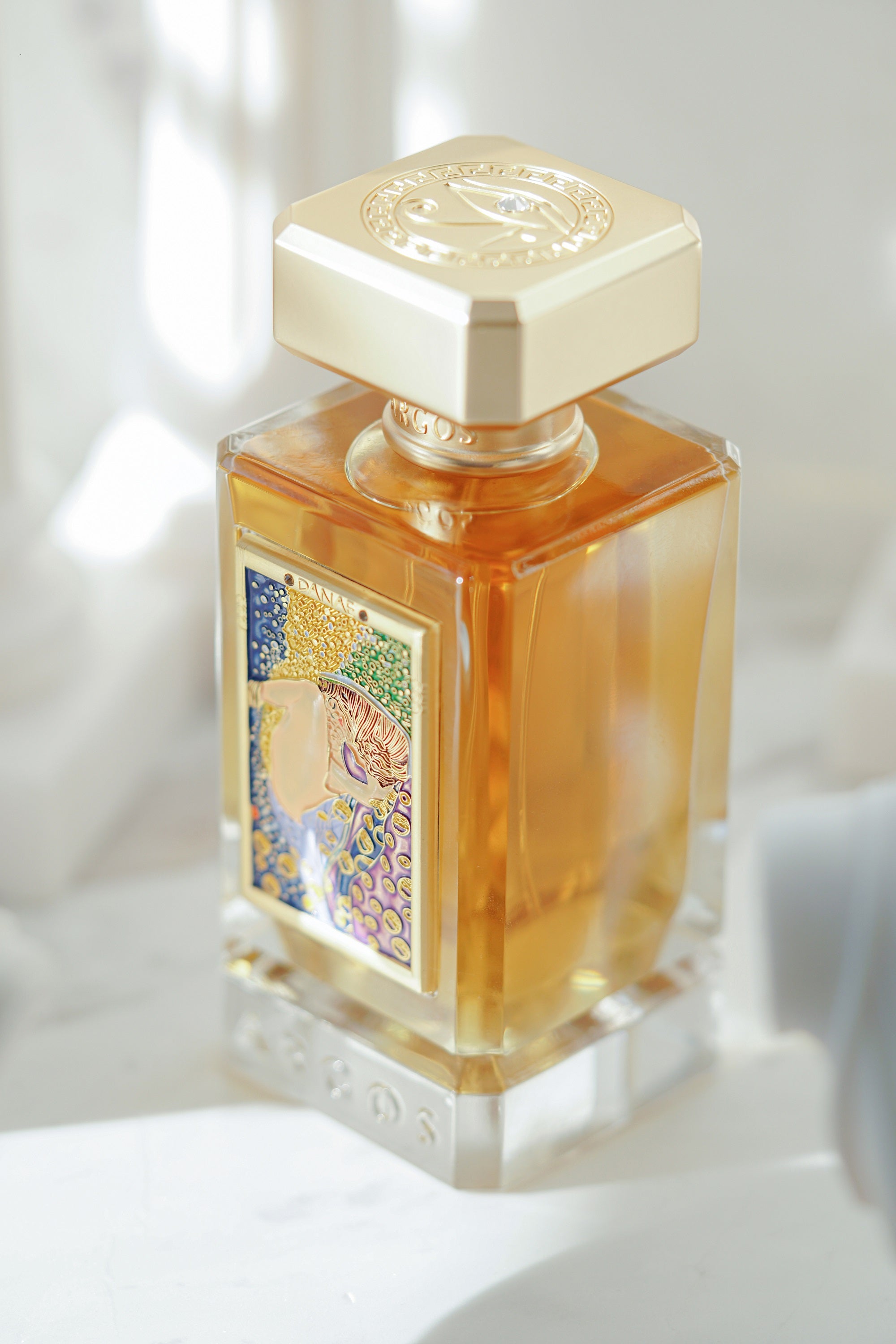 Argos Fragrances New Release DANAE 100ml Bottle Top Left View Surrounded with Artistics Sculptures
