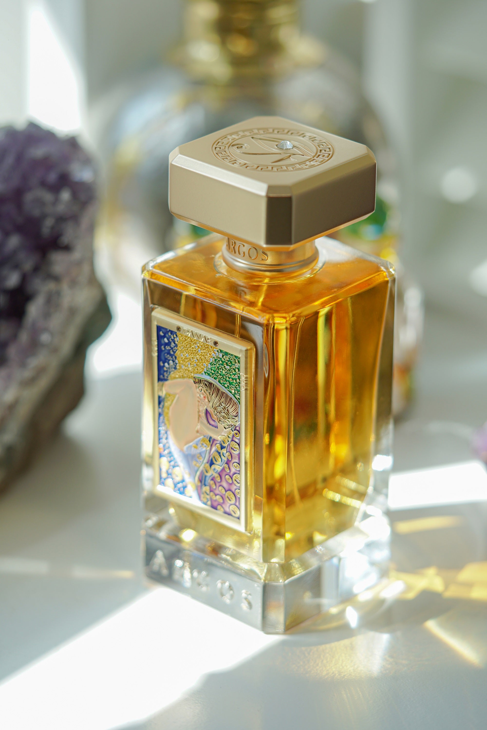 Argos Fragrances New Release DANAE 100ml Bottle Top Left View Surrounded with Artistics Ornaments
