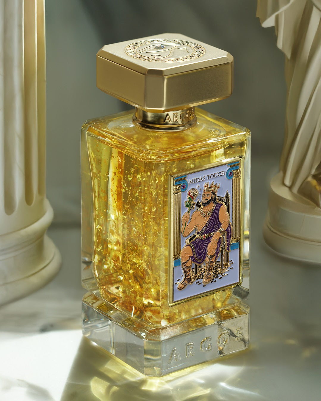 Argos Midas Touch 24K Gold perfume bottle with decorative label on a reflective surface