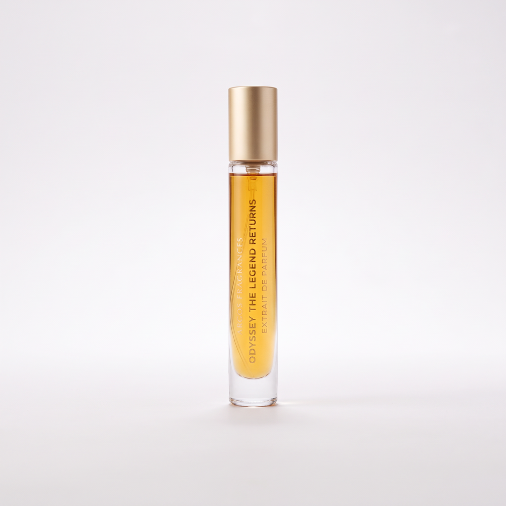 A clear glass rollerball perfume bottle filled with amber liquid, featuring a metallic gold cap and vertical gold text that reads 'ODYSSEY THE LEGEND RETURNS'. The bottle is centered on a seamless light gray background.