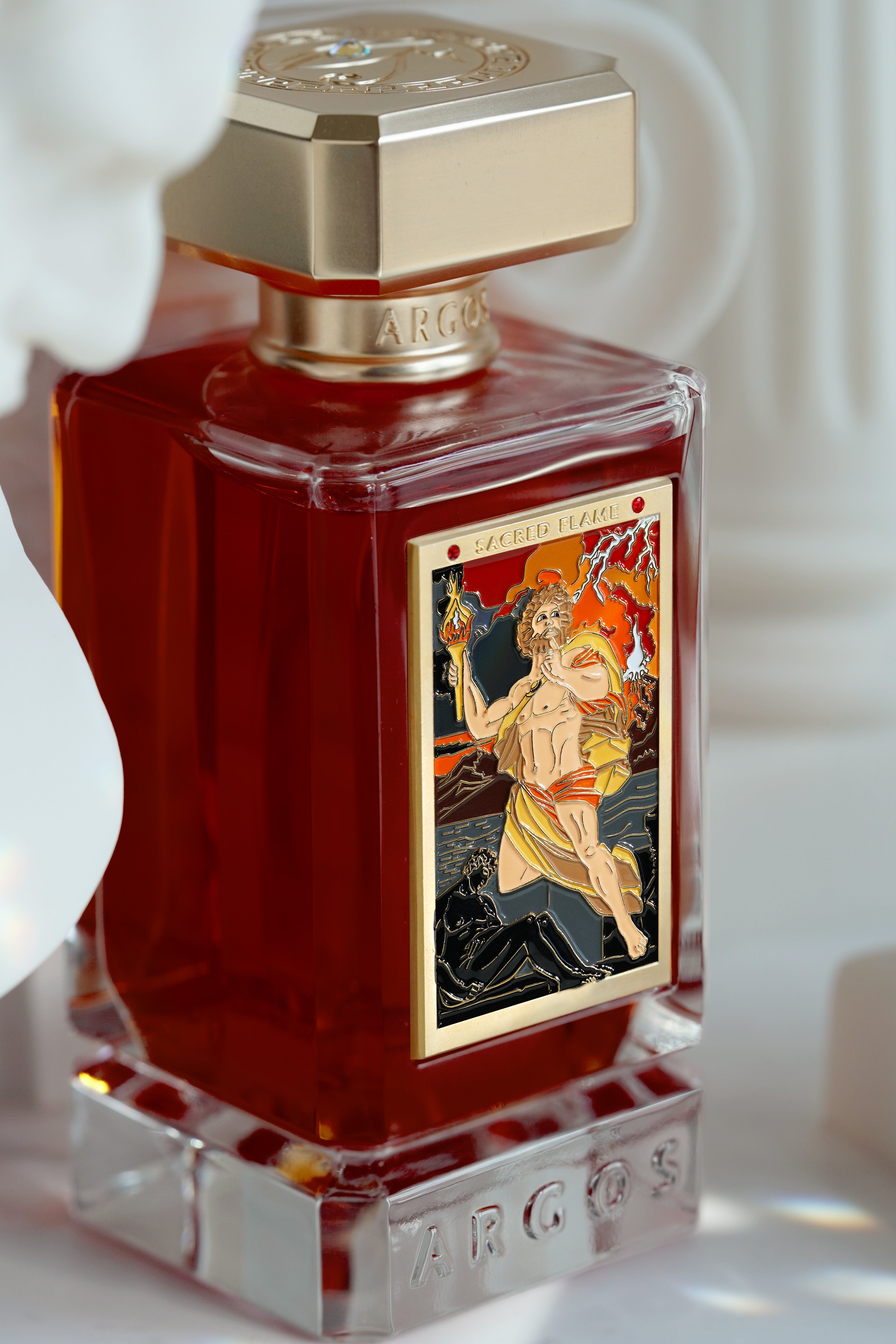 Artistic lighting on Sacred Flame perfume bottle emphasizing glass and gold features.